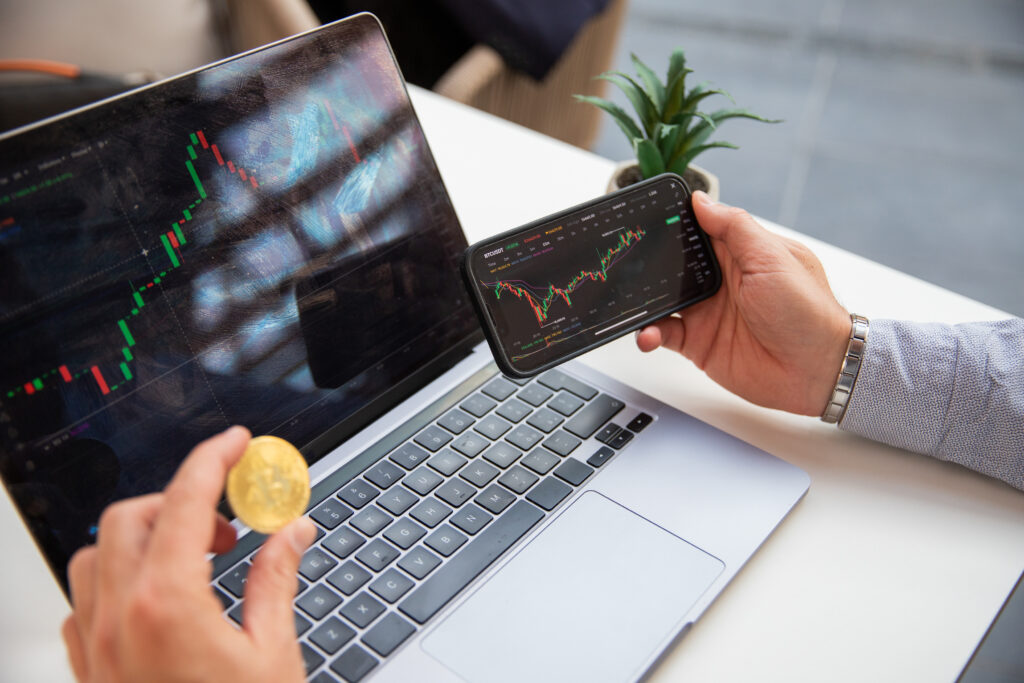 Is It Safe to Invest in Crypto: A cryptocurrency trader trades with his laptop and smartphone