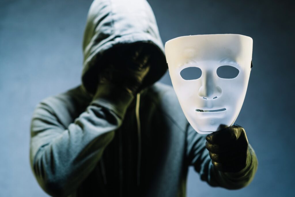 A scammer holding a mask