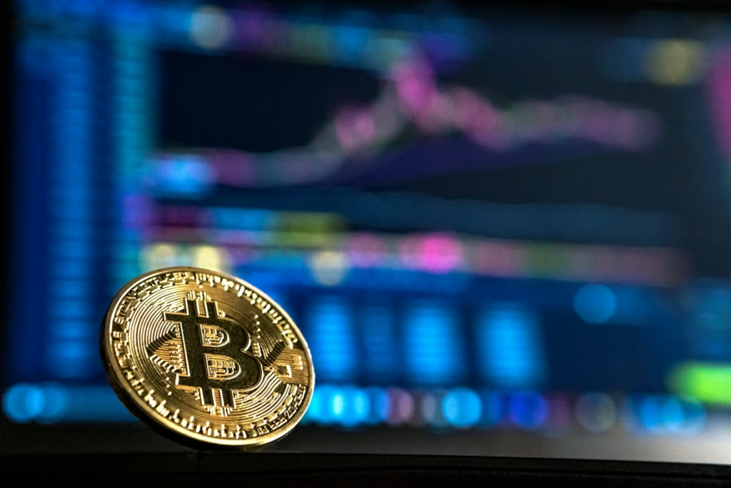 Gold colored Bitcoin in front of a screen