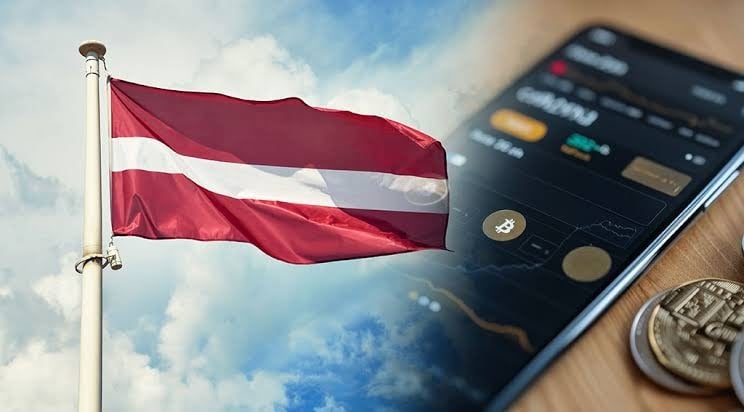 The Latvian flag and a smartphone displaying cryptocurrency prices and charts.
