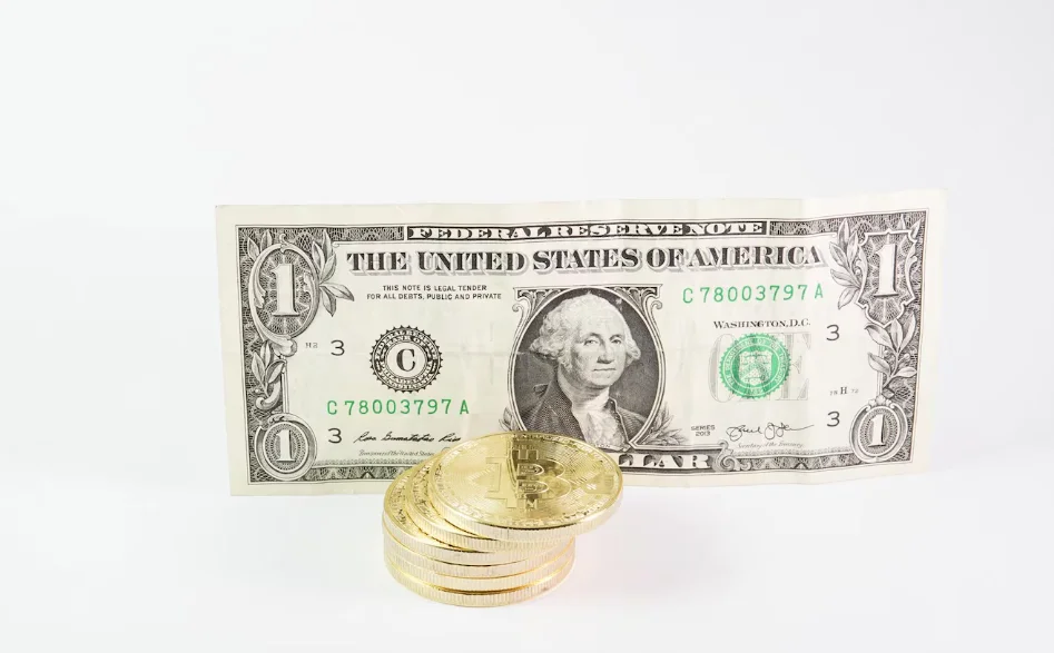 Bitcoins stacked with a dollar bill on a white background