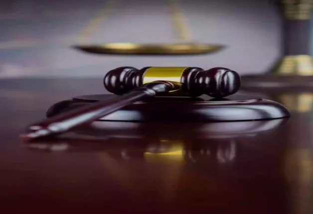A gavel in focus with the scale of justice behind a blurred background