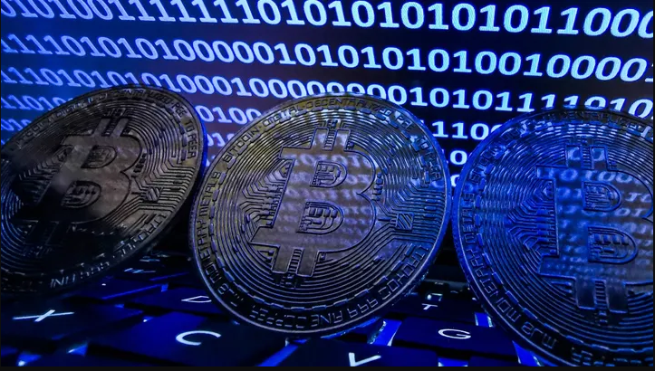 Three large Bitcoins against system numeral placed against a screen and system keypads
