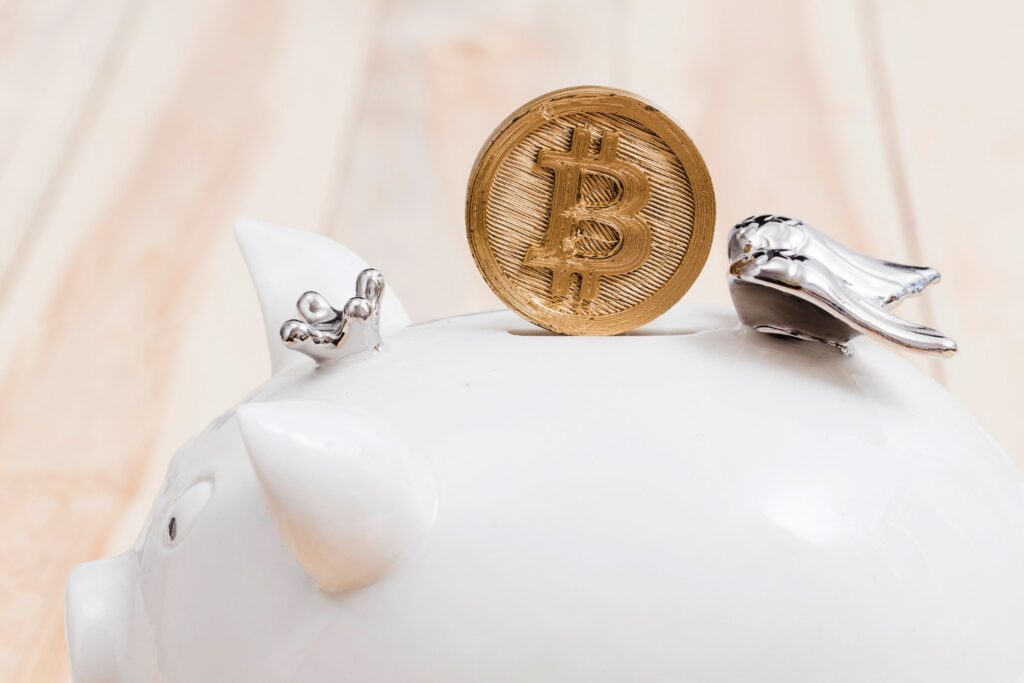 Golden Bitcoin over the slot of a white piggybank