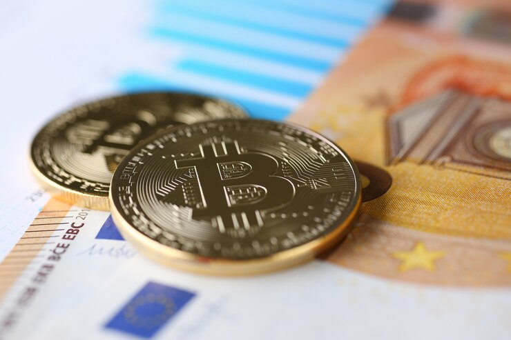 Two Bitcoin coins placed on top of a Euro banknote, representing cryptocurrency and traditional currency