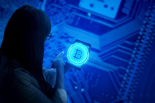 Woman pointing at a smartphone screen displaying a glowing Bitcoin symbol