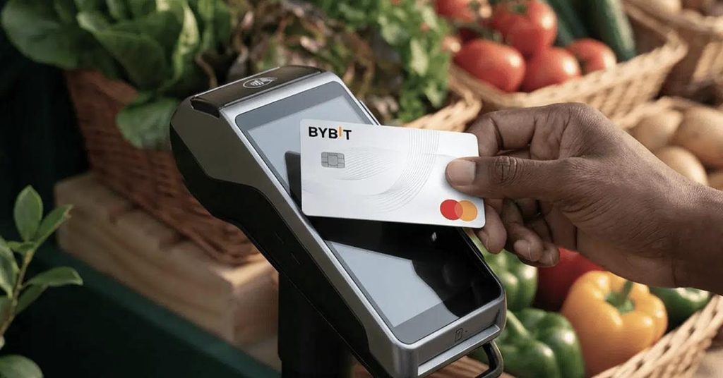 Bybit card placed on a POS machine with baskets of vegetables in the background