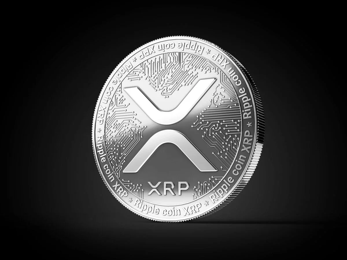 Silver XRP cryptocurrency coin featuring the XRP logo against a dark black background.