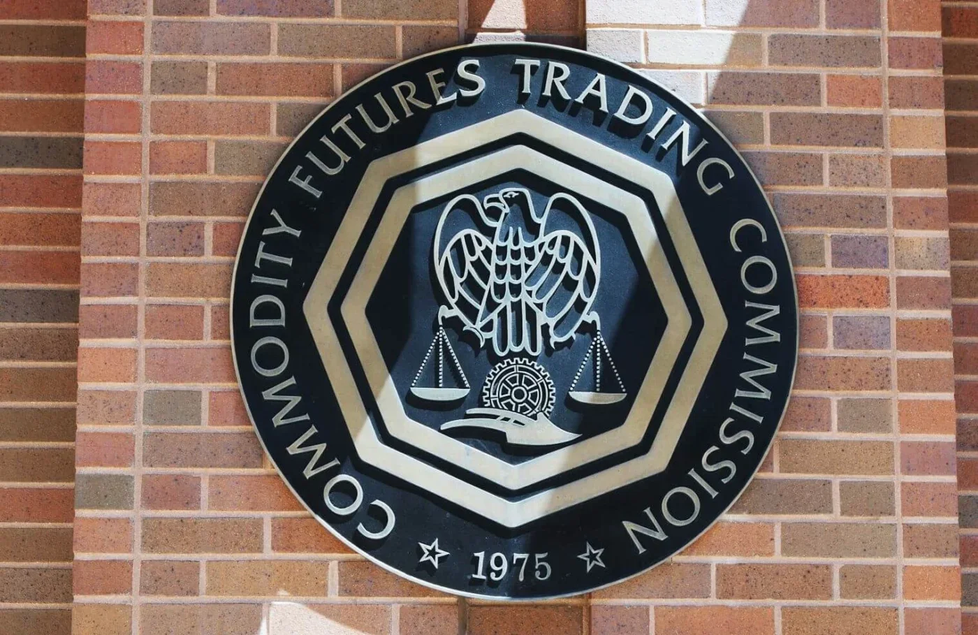 U.S. Commodity Futures Trading Commission (CFTC) seal mounted on a brick wall.