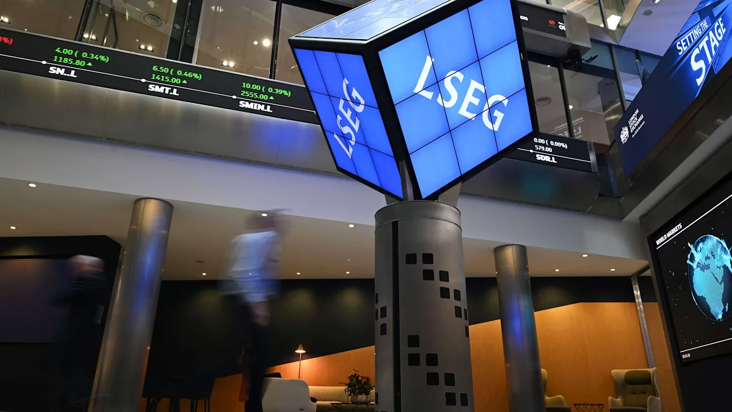 Interior of the London Stock Exchange with LSEG digital displays and live market price tickers.