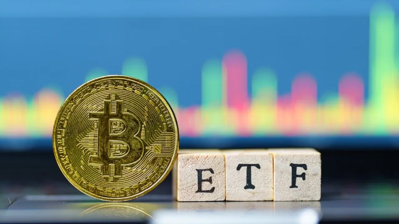 Una moneta Bitcoin accanto a dei blocchi che compongono la scritta "ETF", con un grafico sfocato del mercato finanziario sullo sfondo.