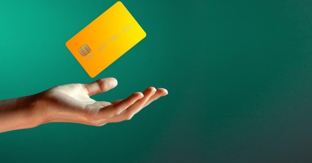 image displays a gold card floating above a hand set against a green background